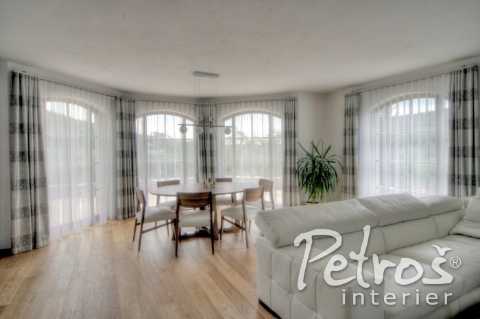 TYPICKÝ PŘÍKLAD MODERNÍHO ELEGANT STYLU. Interiéru dominuje lehký moderní nábytek v měkkých pastelových barvách, vše zde působí vzdušně, moderně, jednoduše, ale zároveň velmi luxusně. Designér Radomír Petroš k tomuto interiéru vybral závěsy v kouřově šedé barvě se vzorem, který na závěsech vytváří horizontální pruhy. Záclony a závěsy jsou nařaseny na Wave systém a zavěšeny jsou na moderní hranaté garnýže Square line.
