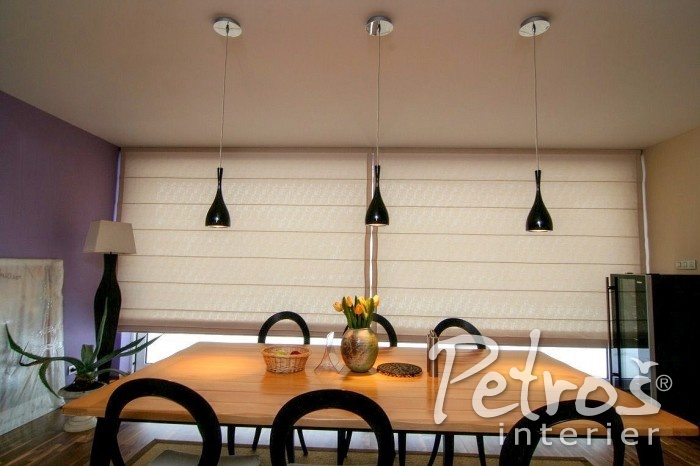 TAKÉ ŘÍMSKÉ ROLETY MOHOU BÝT K MODERNÍMU ELEGANT STYLU TO PRAVÉ. Jídelna s tímto krásným designovým nábytkem si přímo říkala o perfektně propracovanou římskou roletu z hladké jednobarevné látky. V jednoduchosti je krása - a v tomto přímočarém moderním interiéru to platí dvojnásob. Měkce průsvitná látka dává vyniknout elegantním liniím římské rolety. Další vzory či řasení dekorací by jen zbytečně odváděly pozornost od ušlechtilého designu nábytku. Tato římská roleta je z dílny Petroš interier.